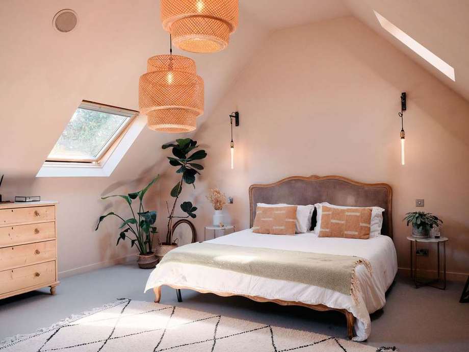 The bed under the vaulted ceiling with a rattan pendant