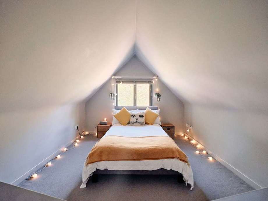 Bed tucked under the arched eaves, lit by candles